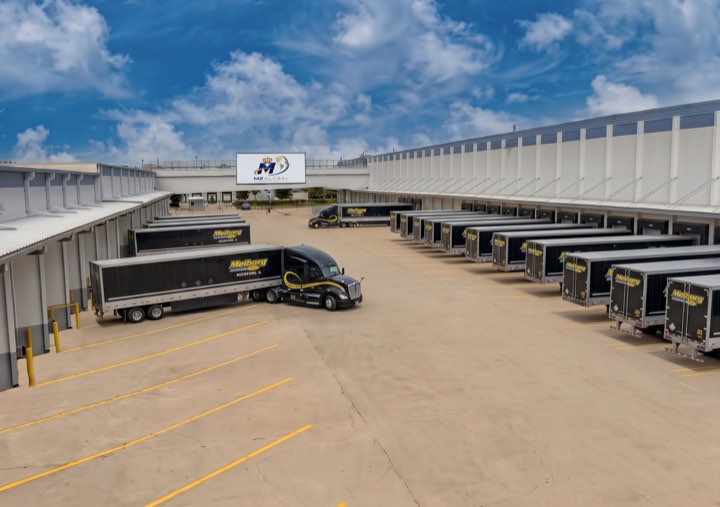 Meiborg trailers backed into the loading docks beneath the M2 Global sign on the building face.