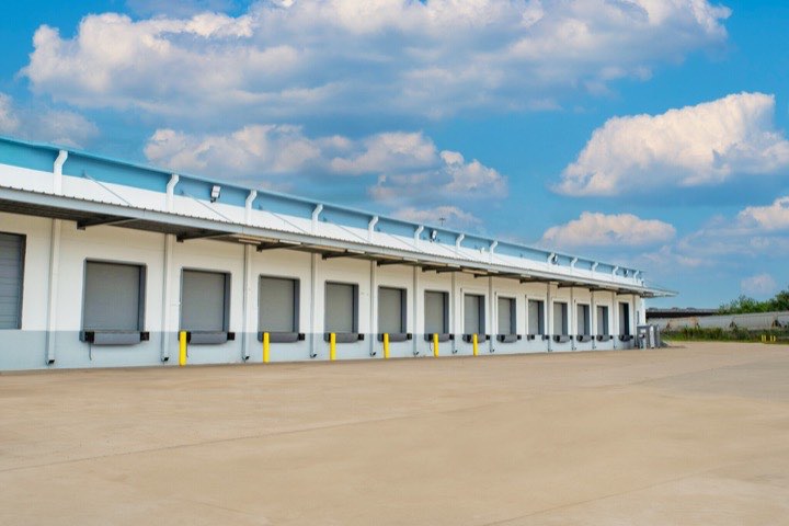 A row of dock high doors along the building exterior under a blue sky.
