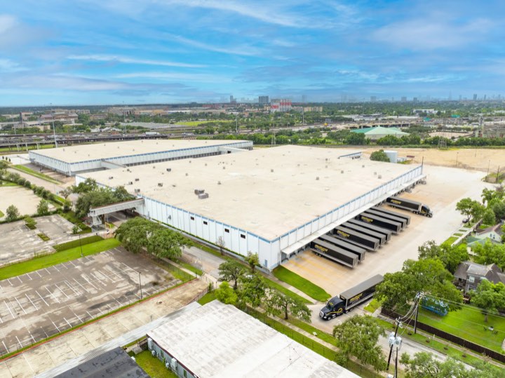 Aerial view of the campus with trailers lined along the dock face and the Houston skyline beyond.
